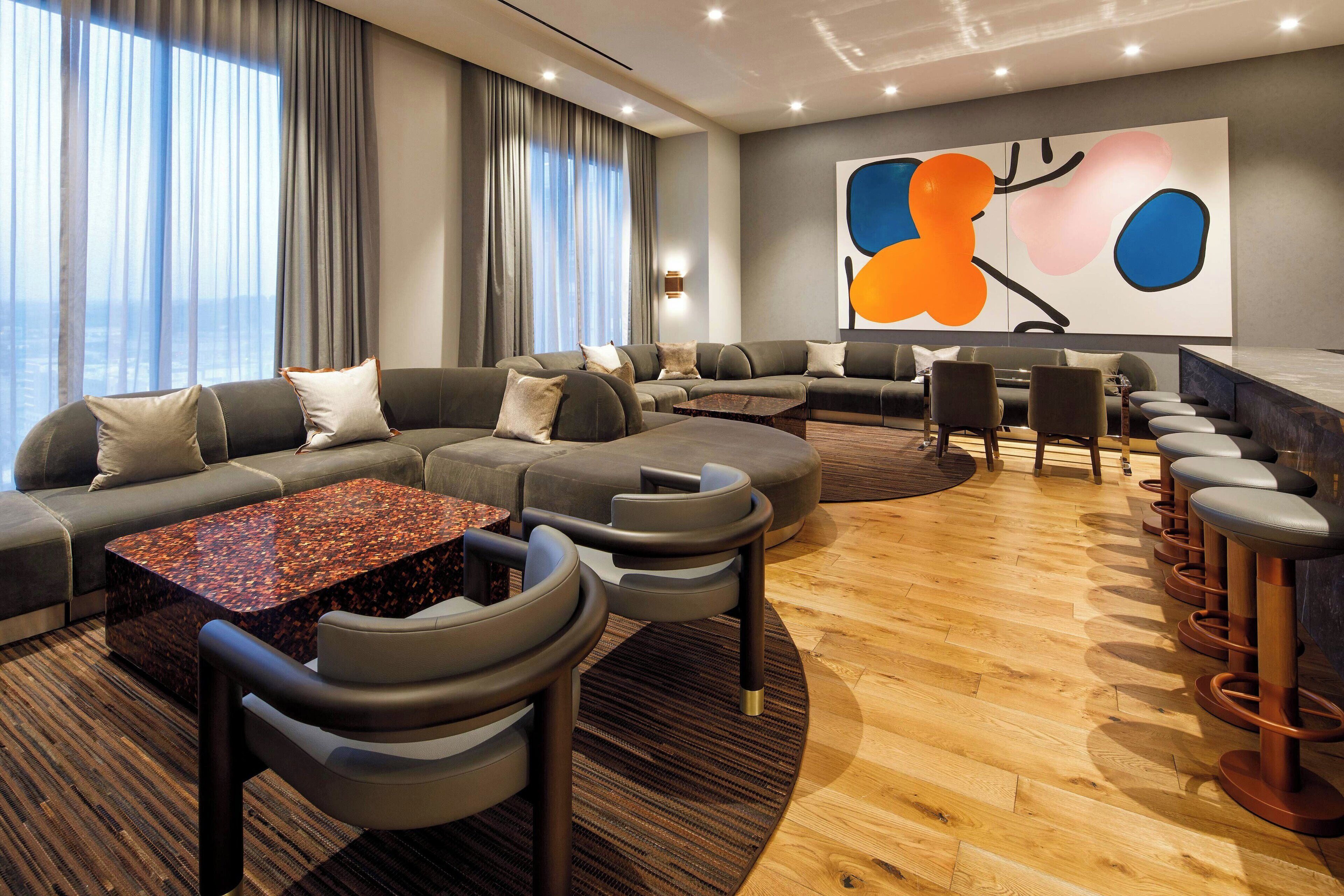 A modern lounge area with a sectional sofa, a coffee table, and a bar with stools.