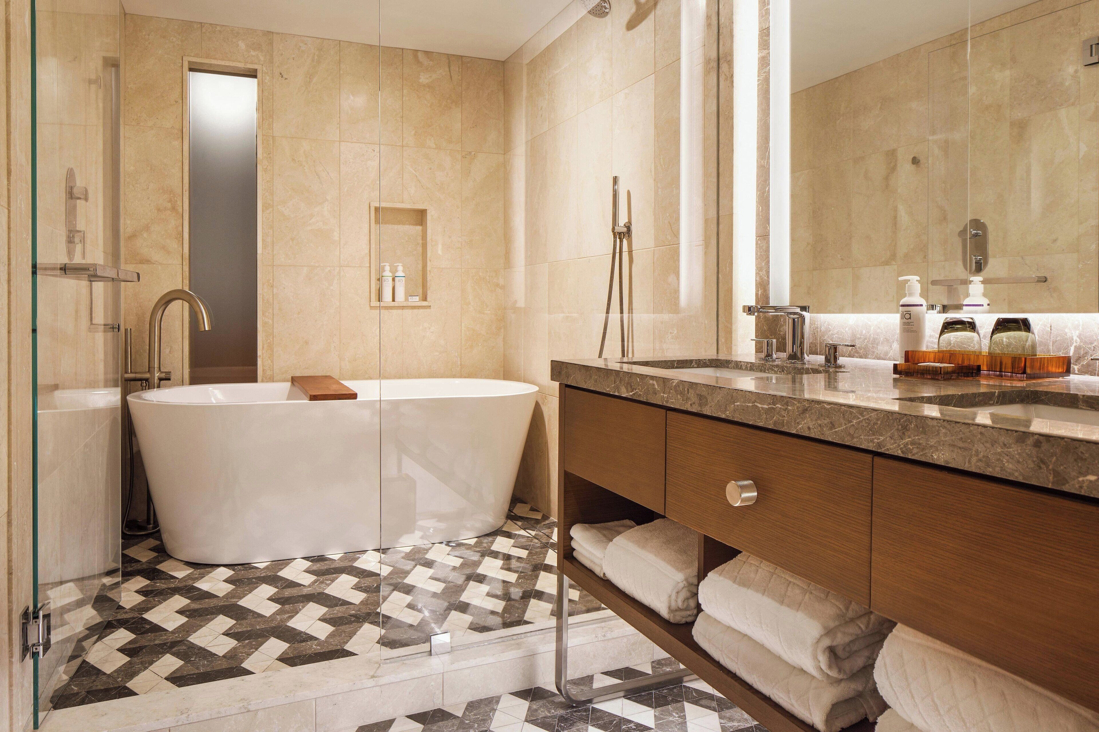 Une salle de bain moderne avec une baignoire sur pieds, un meuble-lavabo avec un miroir et un sol carrelé.