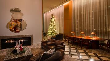A modern living room with a fireplace, a Christmas tree, and a dining area with a table and chairs.
