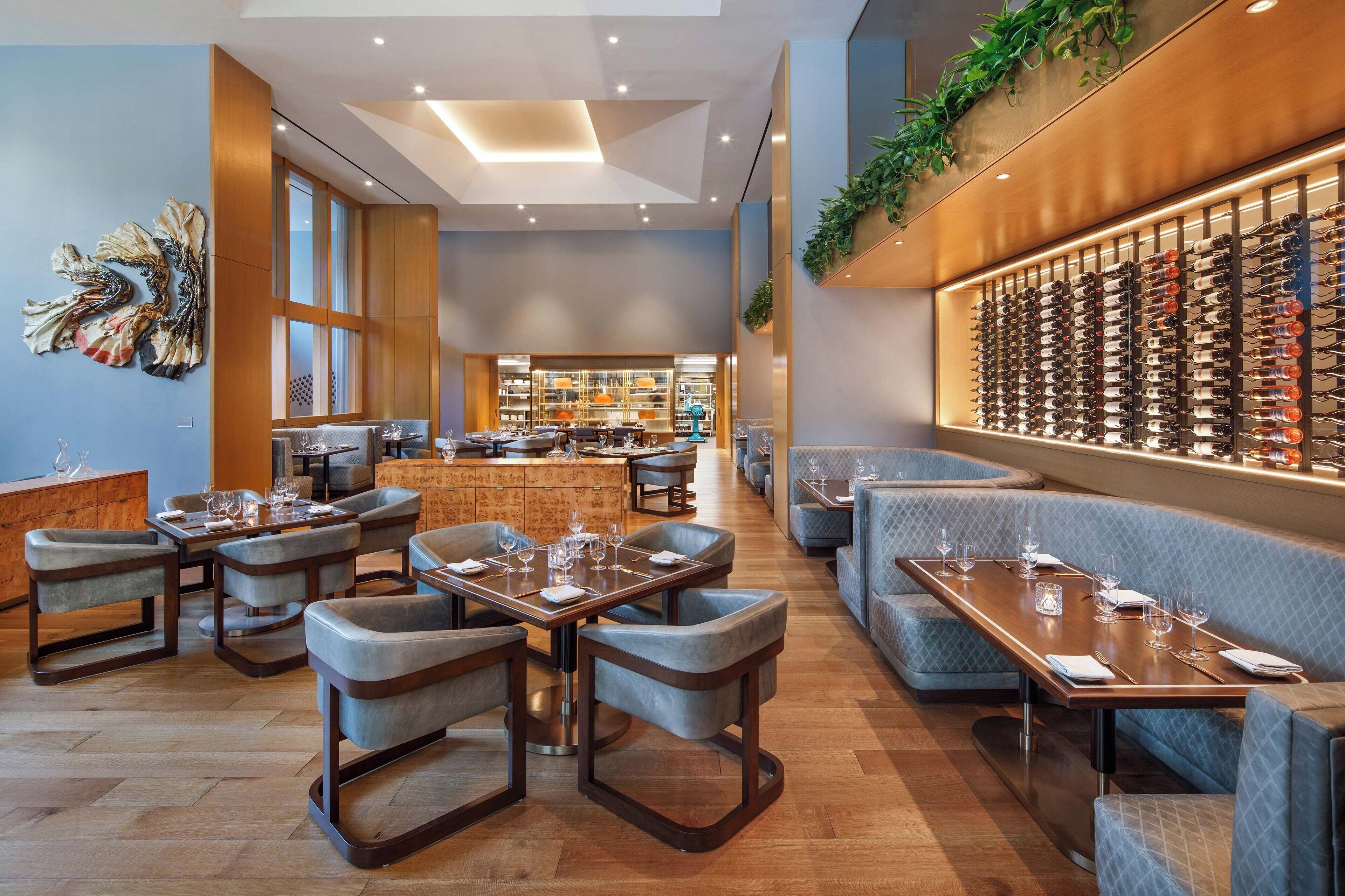 A modern restaurant with a bar area, seating arrangements, and a wine display.