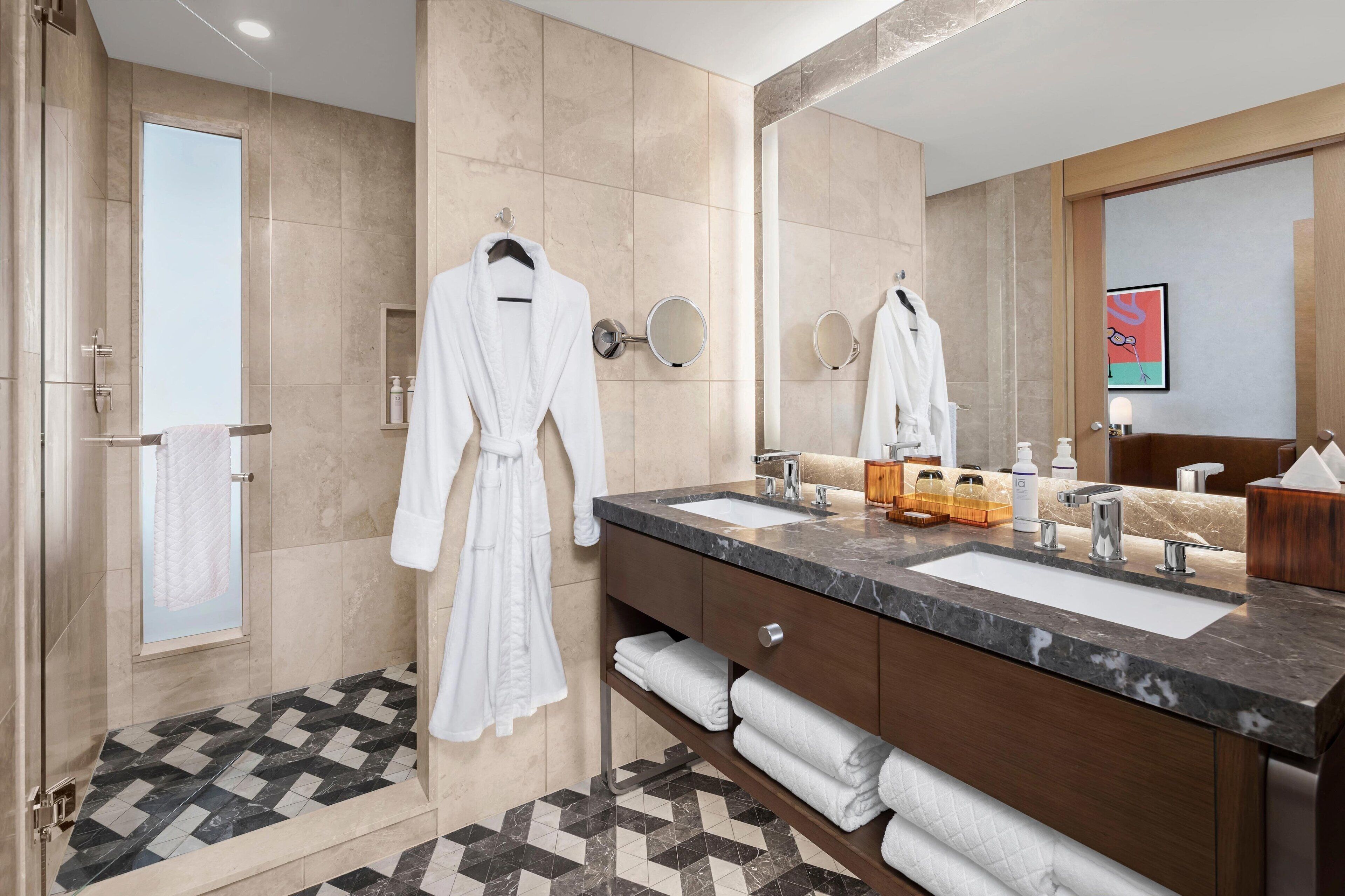 Un baño moderno con un espejo grande, dos lavamanos y una ducha a pie.