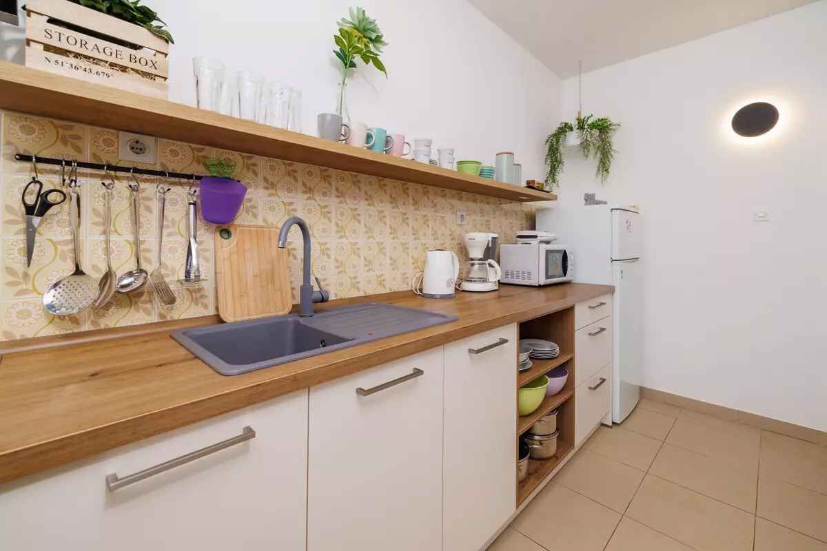 Une cuisine avec un plan de travail en bois, un évier et une boîte de rangement étiquetée « BOÎTE DE RANGEMENT ».