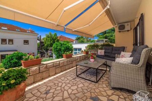 Une terrasse extérieure avec un canapé, une table et des plantes en pot.