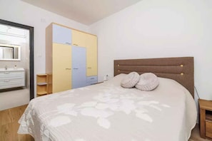 A bedroom with a bed, a wardrobe, a mirror, and a bedside table.