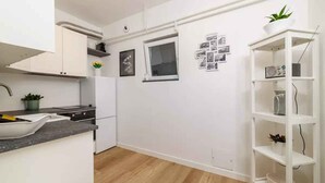 Cozinha moderna com armários brancos, bancada preta e piso de madeira.