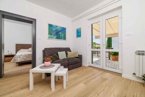 Un salon moderne avec un canapé, une table basse et un lit en arrière-plan.