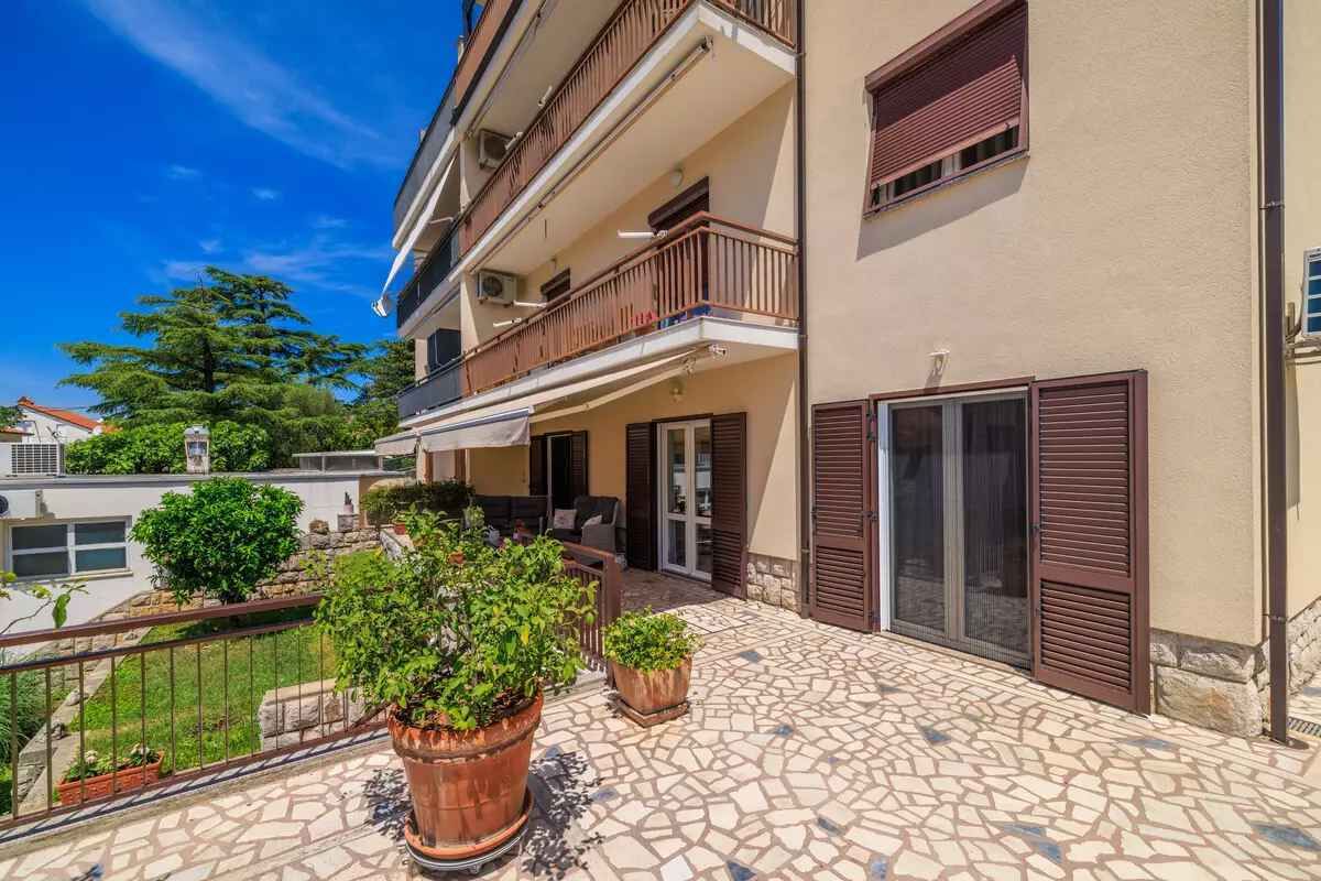 A multi-story building with balconies, a tiled patio, and potted plants.