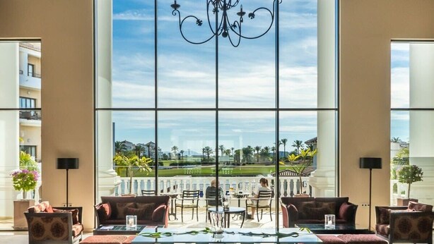 A spacious room with large windows, a chandelier, and a view of a golf course.