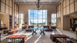 A spacious lobby with a large window, a chandelier, and a central table.