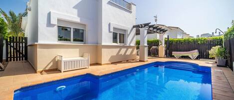 A modern two-story house with a swimming pool, a patio area, and a covered outdoor seating space.