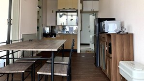 A compact kitchen with a dining area, wooden cabinets, and a microwave. - Big Stone Tsukuda 201 (Aomori)