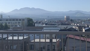 A cityscape with buildings and mountains in the background. - Big Stone Tsukuda 202 (Aomori)