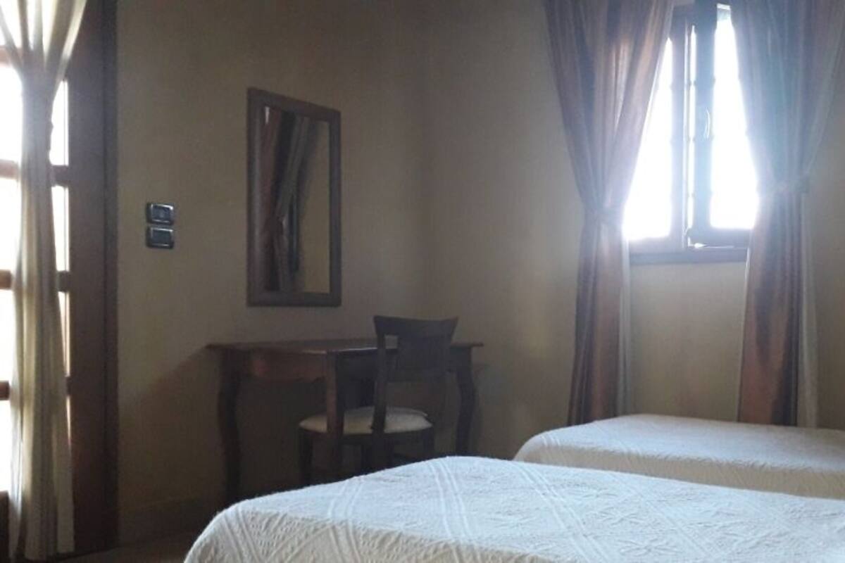 A room with two beds, a desk, and a chair.