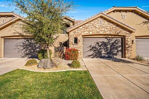 A residential house with a stone facade, two garage doors, a well-maintained lawn, and a tree. - 4098 Coral Ridge, The 19th Hole in Coral Ridge, near golf course, firepit, heated pool, SLP 12 (Washington)
