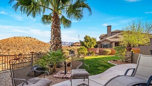 A patio with outdoor furniture, a palm tree, and a house with a hilly backdrop. - 4098 Coral Ridge, The 19th Hole in Coral Ridge, near golf course, firepit, heated pool, SLP 12 (Washington)