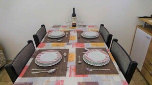 Une table à manger dressée pour quatre personnes, avec des sets de table, des assiettes, des couverts et une bouteille de vin.