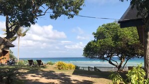 Vista de la playa con cielo despejado, un sendero arenoso y algunas sillas de playa.