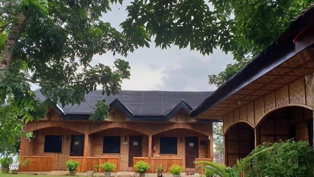 Una casa de madera con porche cubierto y césped.