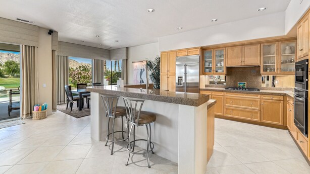 Una cocina moderna con una isla grande, armarios de madera y electrodomésticos de acero inoxidable.