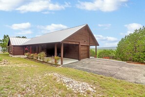 Une grange en bois avec un garage fermé, une décoration en forme d’étoile rouge et une allée gravillonnée.