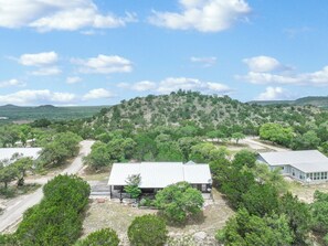 A building with a flat roof, surrounded by trees and a hilly landscape.