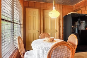 Un intérieur en bois comprenant une table à manger, des chaises, un réfrigérateur et une porte.