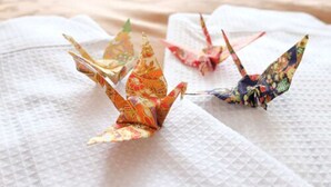 Origami cranes on a textured white surface. - Tokyo BUC Nakagin (Tokyo)