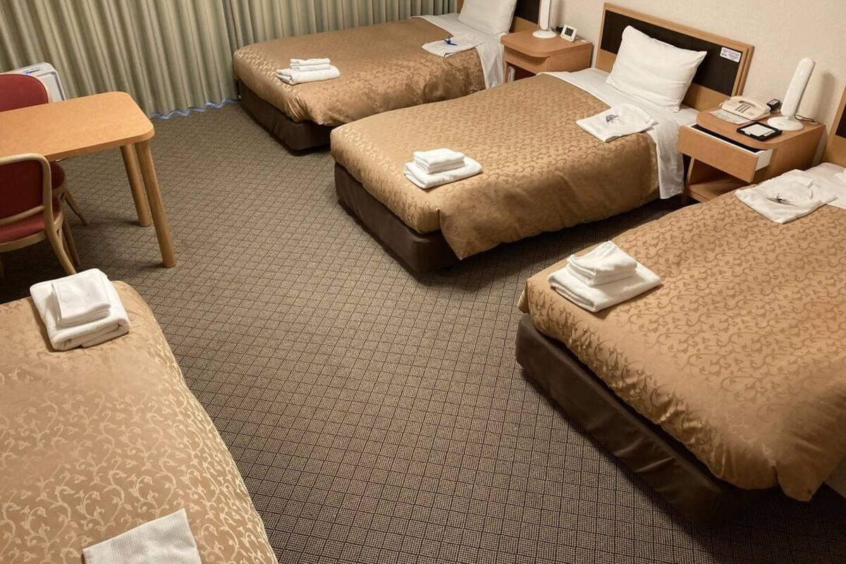 A hotel room with two beds, a desk, a chair, a nightstand, and a telephone.
