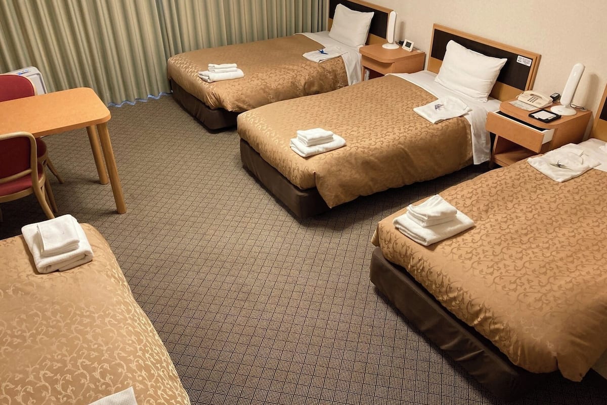 Una habitación de hotel con tres camas, un escritorio y una silla.