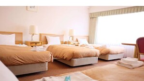 A hotel room with three beds, each with a white pillow and a beige blanket. There are two bedside tables with lamps, and a chair is visible in the corner. - Tokyo BUC Nakagin (Tokyo)