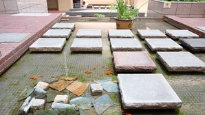 A tiled courtyard with stone slabs and a fish pond. - Tokyo BUC Nakagin (Tokyo)