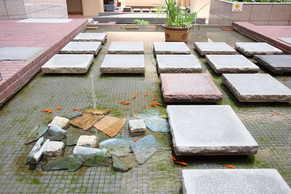 A tiled courtyard with stone slabs and a fish pond.