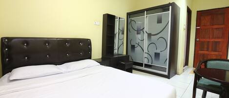 A hotel room with a large bed, a wardrobe, a desk, and a chair.