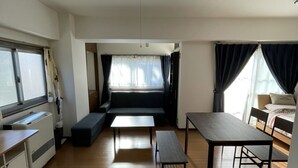 A compact living space with a kitchenette, a sofa, a dining table, and a bed. - G&R House 101 (Tokyo)