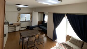 A compact, well-lit room with a bed, a dining table, and a kitchenette. - G&R House 101 (Tokyo)