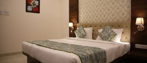 A neatly made bed with a patterned bedspread, a tufted headboard, and two wall-mounted lamps.