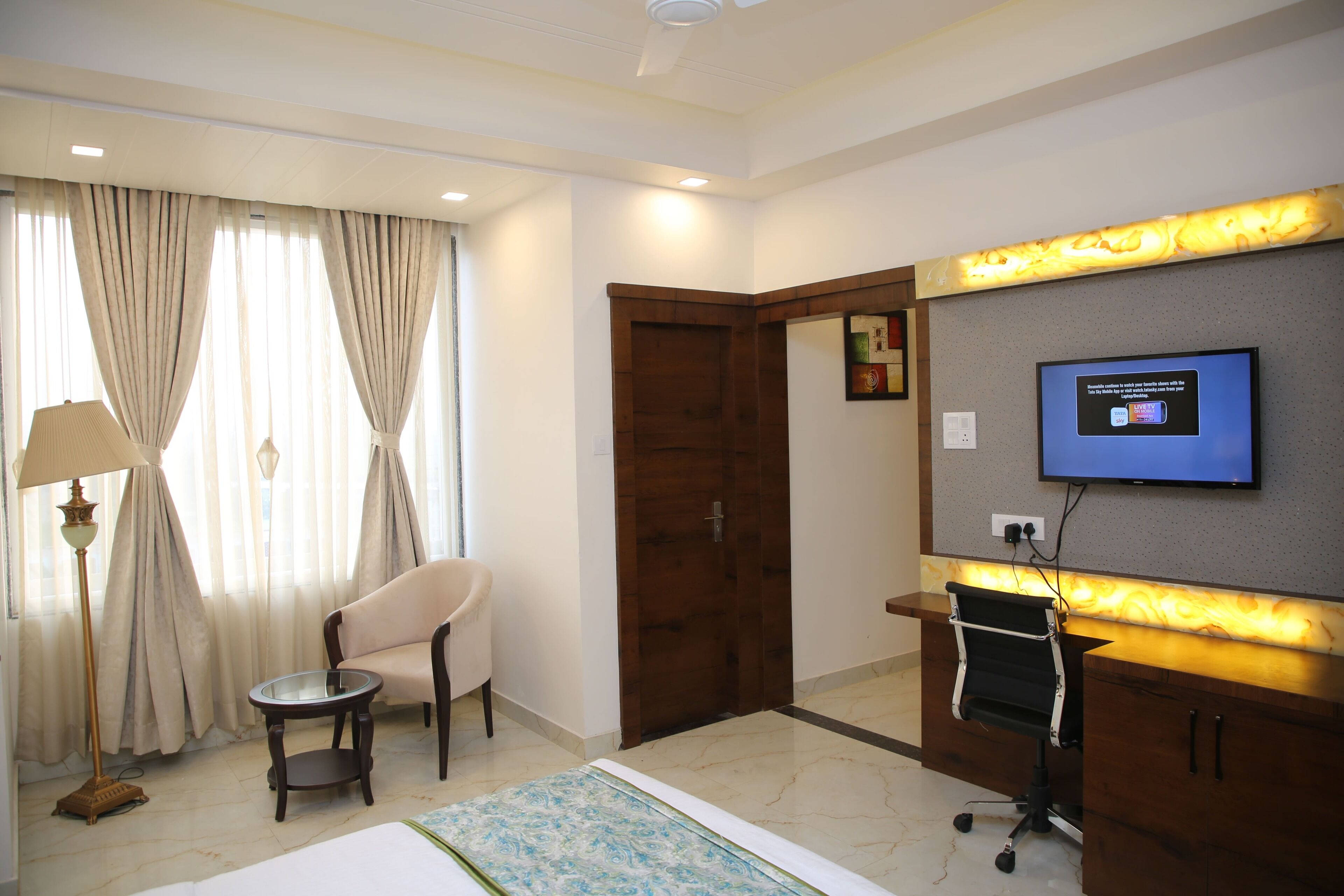Una habitación de hotel con cama, escritorio, silla, televisor y puerta.