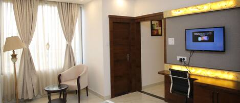Una habitación de hotel con cama, escritorio, silla, televisor y puerta.