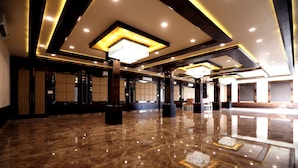 A spacious lobby with a polished marble floor, recessed lighting, and a large chandelier.