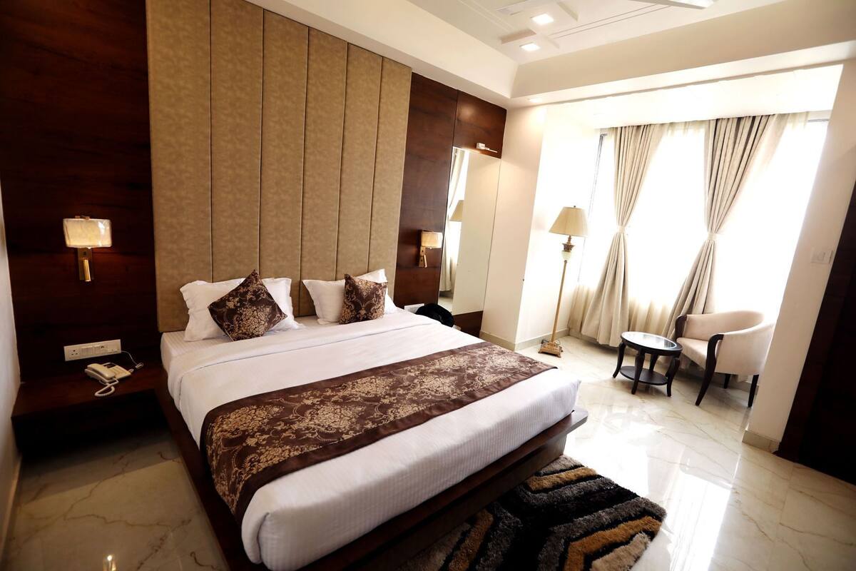 A hotel room with a large bed, bedside lamps, a desk, a chair, and a view of the outdoors.