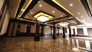 A spacious lobby with a polished marble floor, recessed lighting, and a central chandelier.