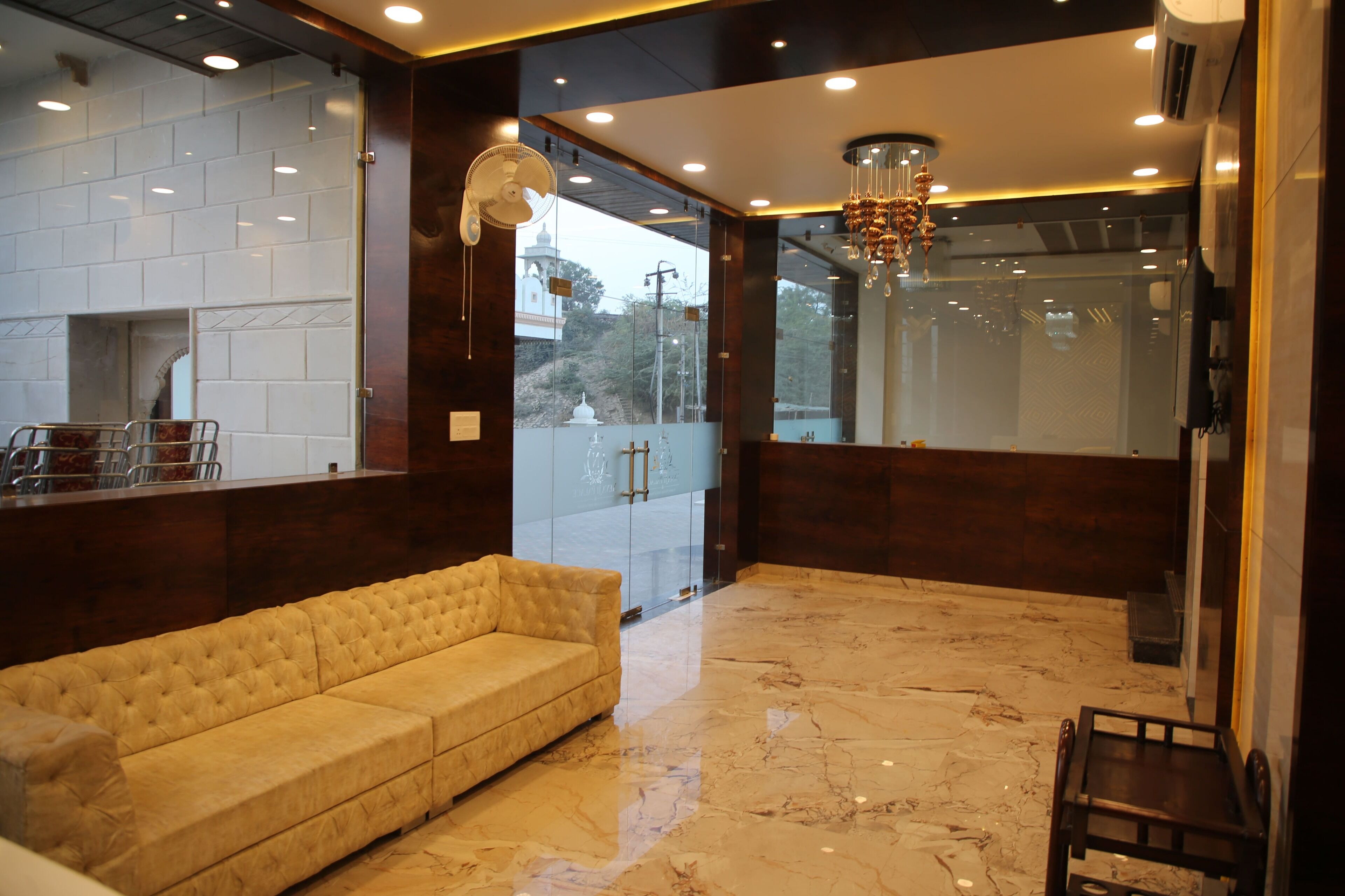 A lobby with a marble floor, a beige sofa, and a chandelier.