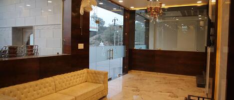 A lobby with a marble floor, a beige sofa, and a chandelier.