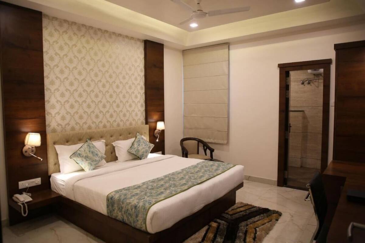 A hotel room with a large bed, bedside lamps, a ceiling fan, and a door leading to a bathroom.