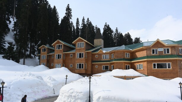 A large wooden building with multiple windows and a green roof, surrounded by snow and trees. - Kolahoi Green Heights Gulmarg (Baramula)