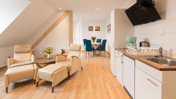 A modern kitchen with a wooden countertop, white cabinets, and a black range hood. - Hotel Ludwig (Munich)