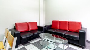 A room with a black and red sofa set, a glass coffee table, and a checkered floor. - SPOT ON 2272 Citra Arcade Residence Syariah (Medan)