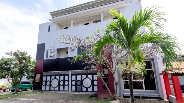 A modern building with a white facade, black and red accents, and a gated entrance. - SPOT ON 2272 Citra Arcade Residence Syariah (Medan)
