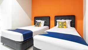 A hotel room with two beds, each with a black headboard and white bedding. The walls are orange, and there is a white ceiling with a skylight. - SPOT ON 2272 Citra Arcade Residence Syariah (Medan)