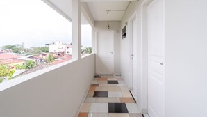 A narrow corridor with a tiled floor, white walls, and a door at the end. - SPOT ON 2272 Citra Arcade Residence Syariah (Medan)